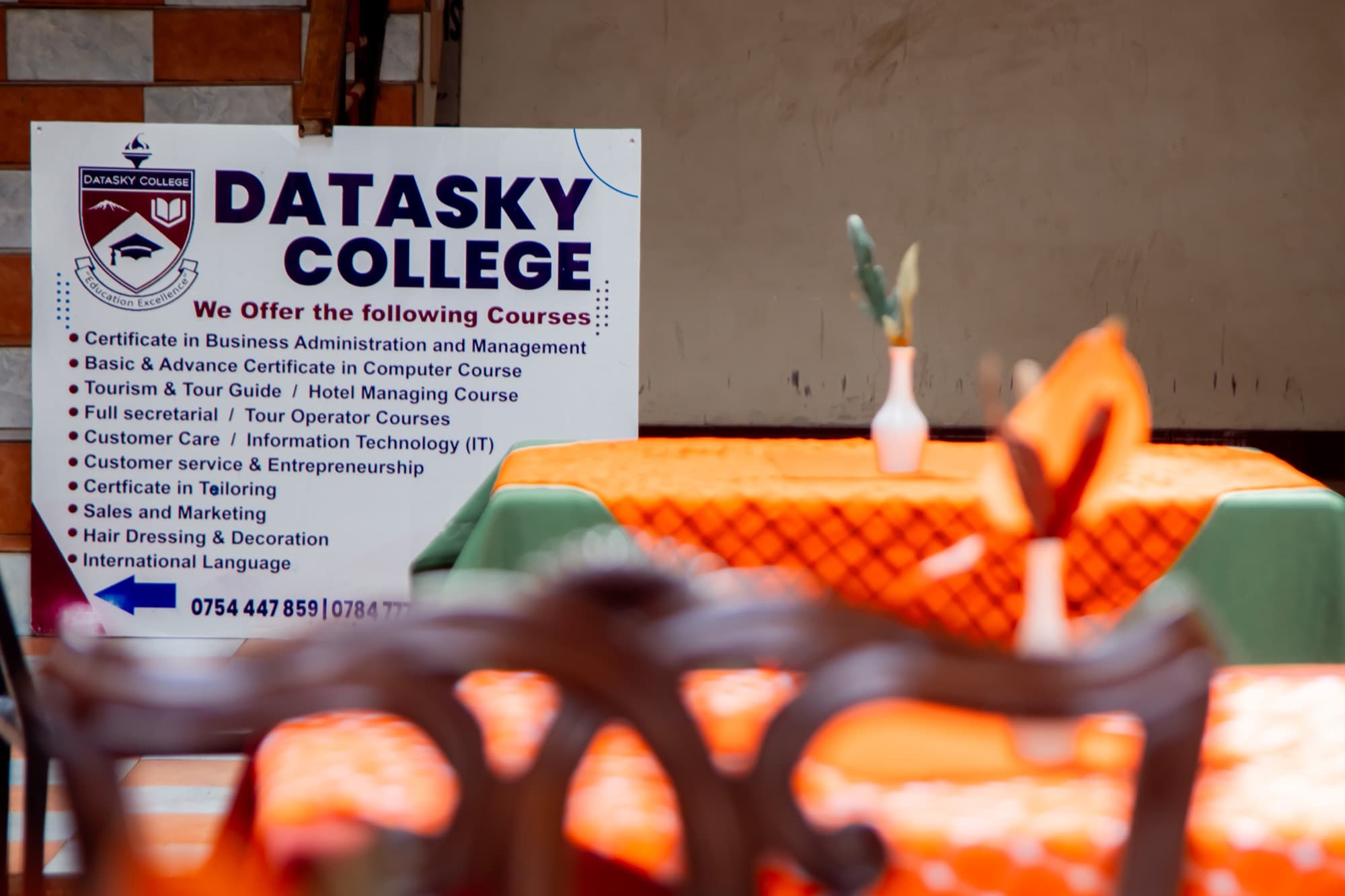 The Datasky College course board on campus, listing tourism, tour guide and hotel management courses