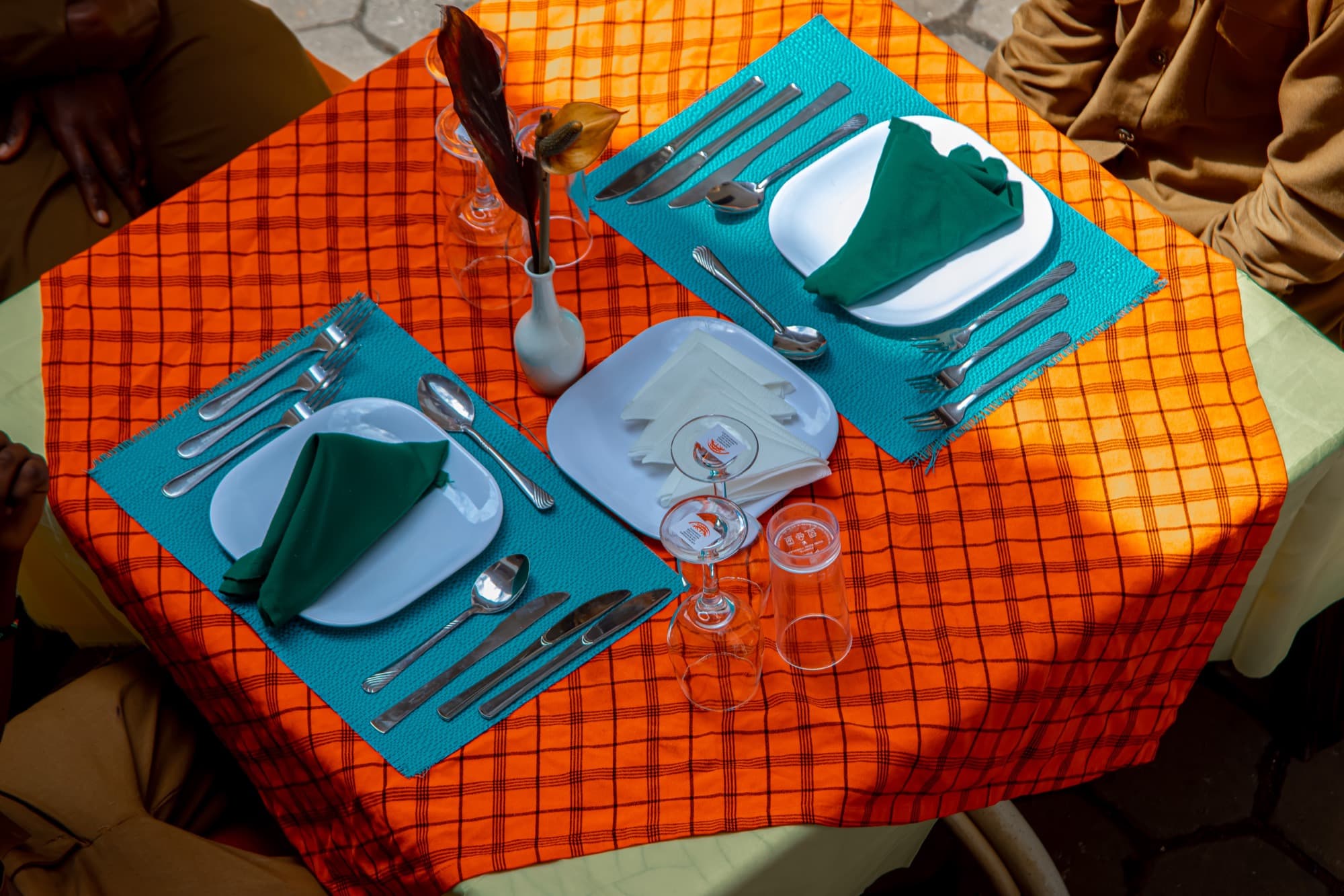 Hospitality students in uniform laying a table with glassware, napkins and a floral arrangement
